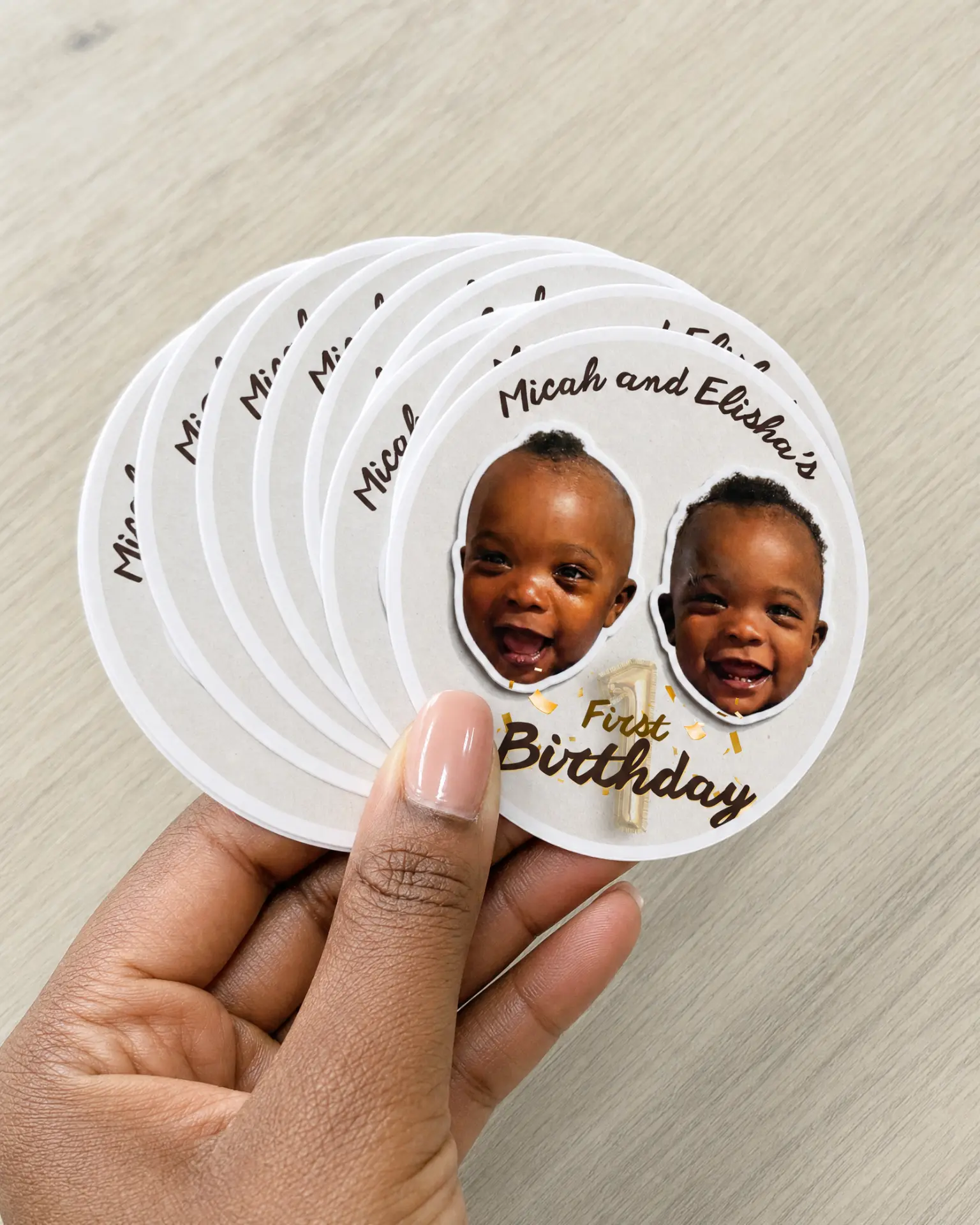 Hand holding a stack of first birthday photo stickers